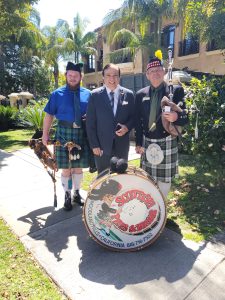Men with bagpipes and drum in garden.